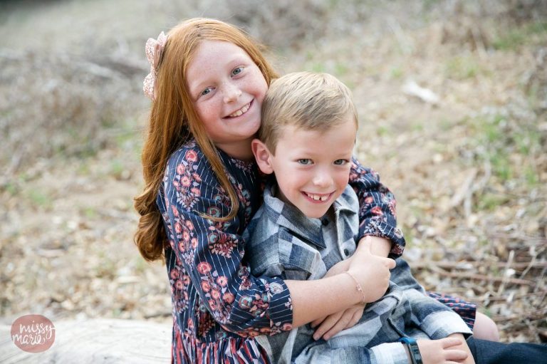 sister hugging brother wearing fall colors