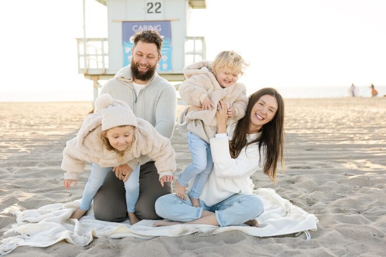 family sitting on the beach laughing
